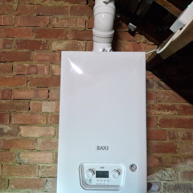 Baxi combi boiler mounted on an exposed brick wall with a new vertical flue, installed by a Gas Safe registered engineer at Downs Plumbing & Heating