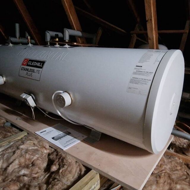 Hot water cylinder installed on boarding in a loft space above the insulation, fitted by Downs Plumbing & Heating in Kent