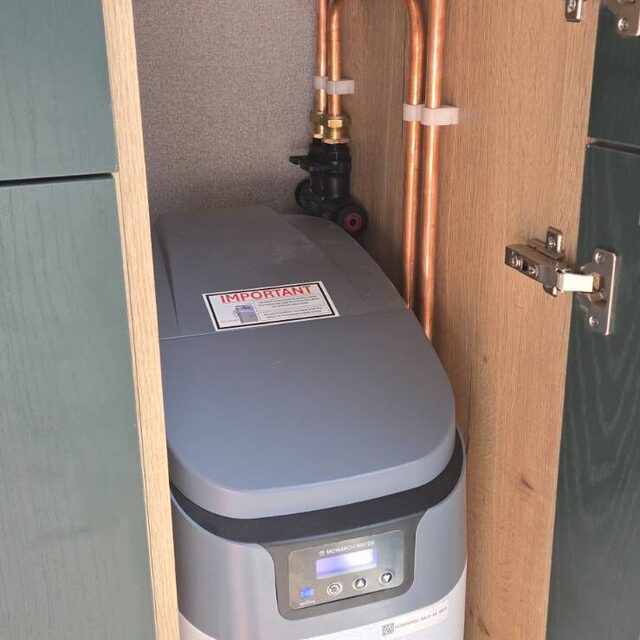 Water softener plumbed into a kitchen cupboard with new copper pipework and isolation valves, installed by Downs Plumbing & Heating